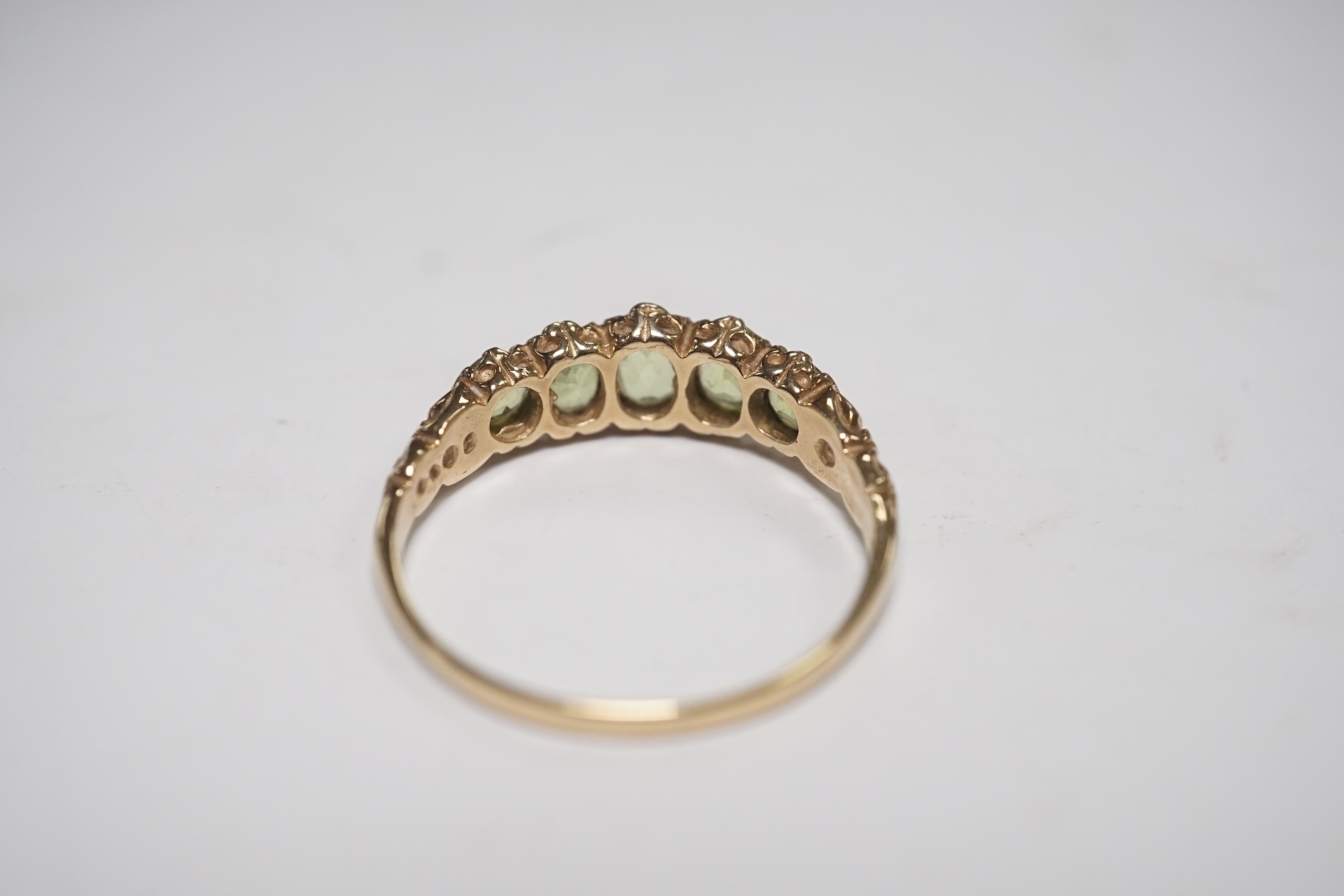 A 9ct and graduated five stone peridot set half hoop ring, size V, a 9ct gold and cameo shell ring and a gem set stickpin. Condition - poor to fair